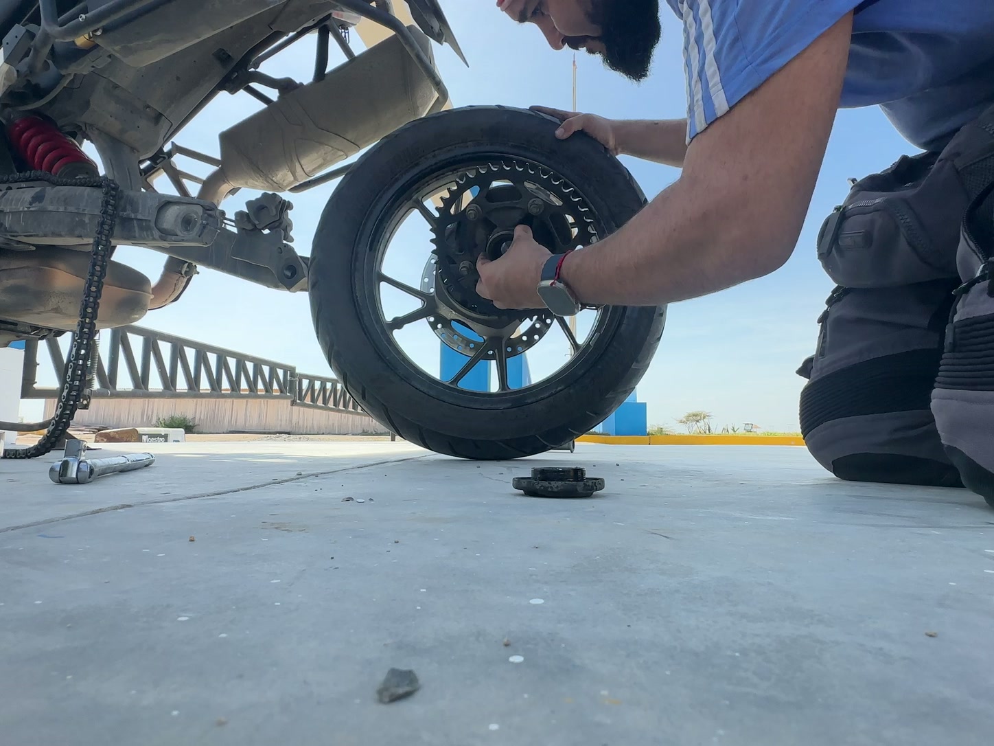 Manos revisando el centro de la rueda desmontada junto a la moto.
